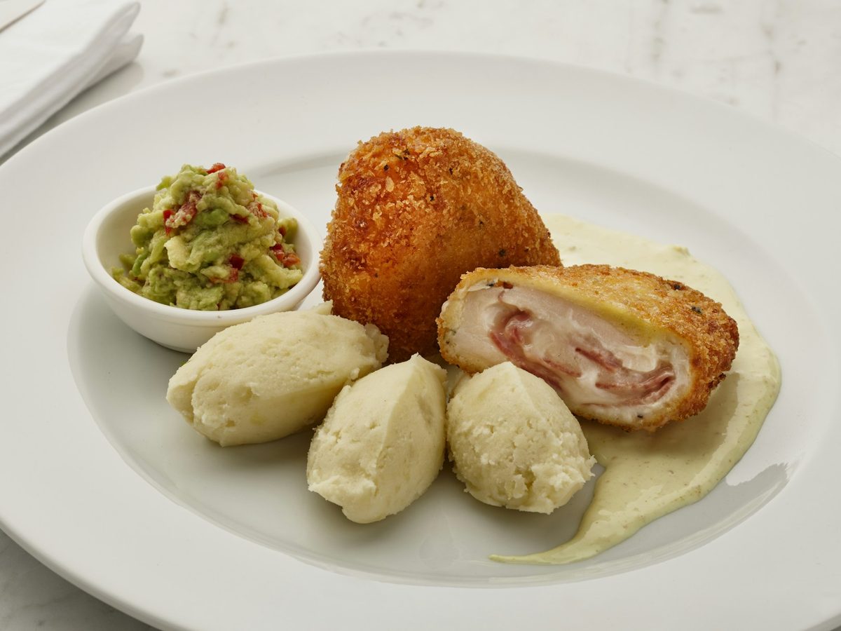 Sliced chicken cordon bleu showing ham and cheese, with potatoes — illustrative